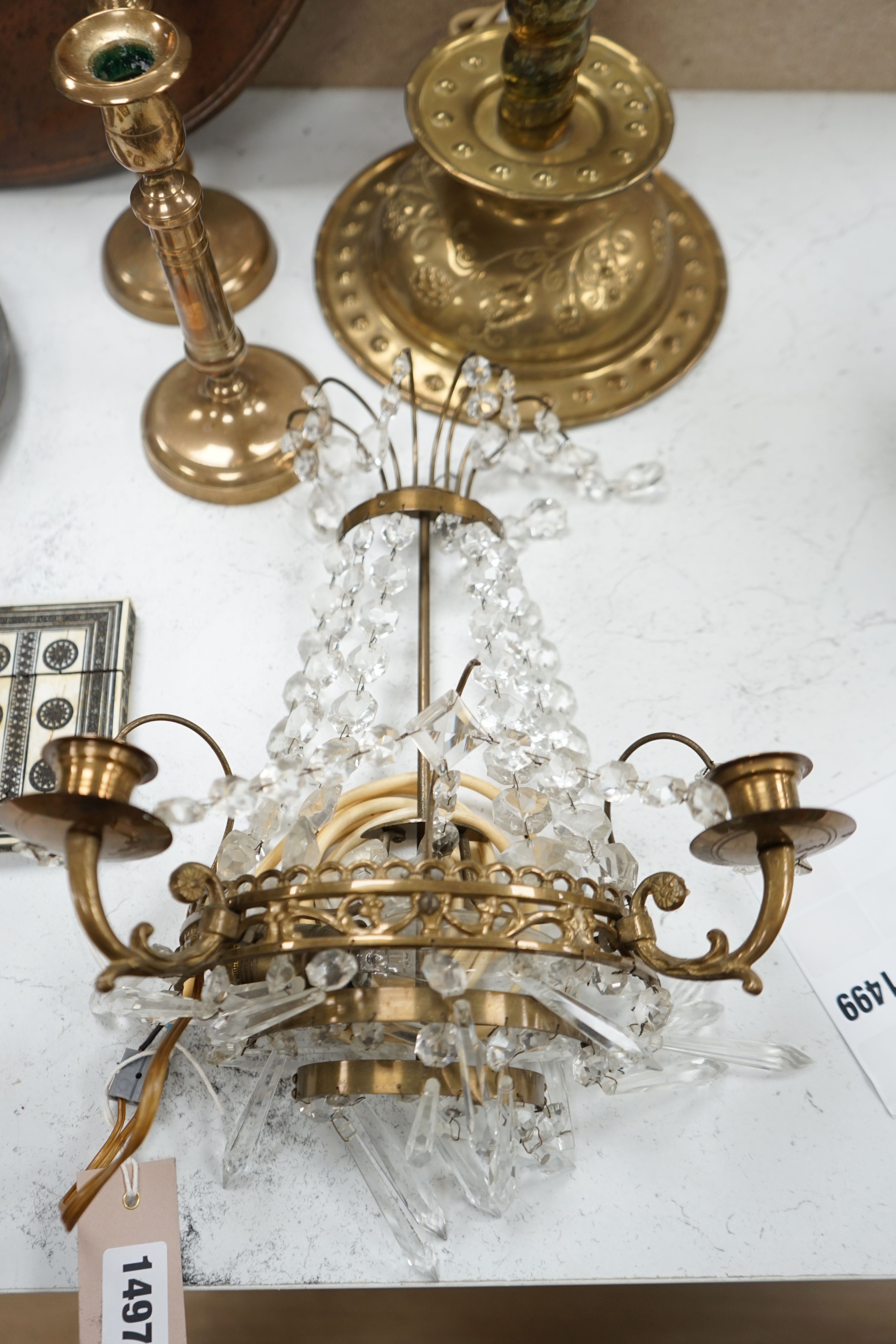 An embossed brass lamp, lustre drop wall light, a pair of bell-metal candlesticks, an 18th century pewter plate and a large Swedish embossed plaque